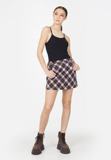 Teenage girl wears the Purple Plaid Girls Mini Skort by Gen Woo with a black cami and chunky boots