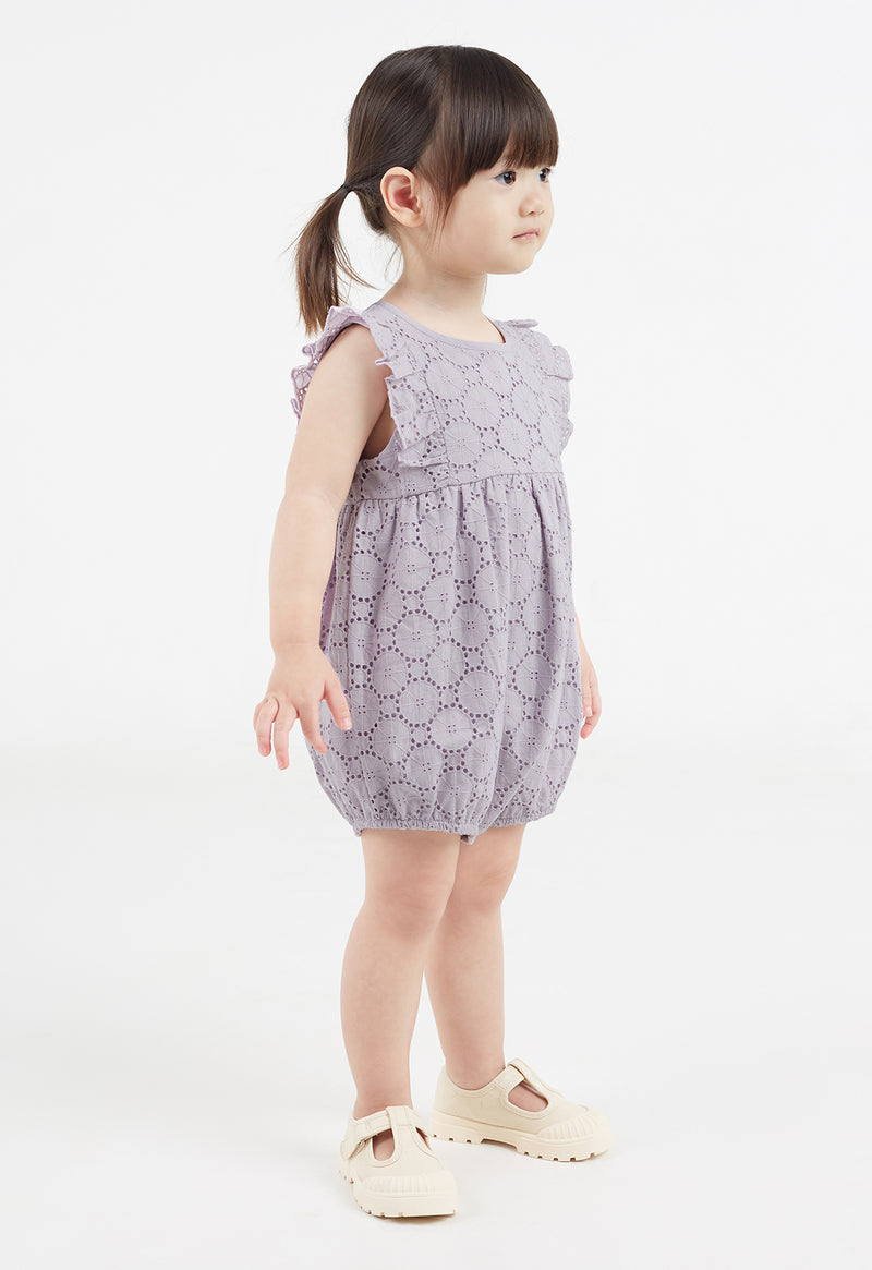 The young girl wears the Lilac Broderie Cotton Baby Romper by Gen Woo