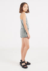 The young girl models the Wash Effect Girls Summer Jumpsuit by Gen Woo with chunky sandals