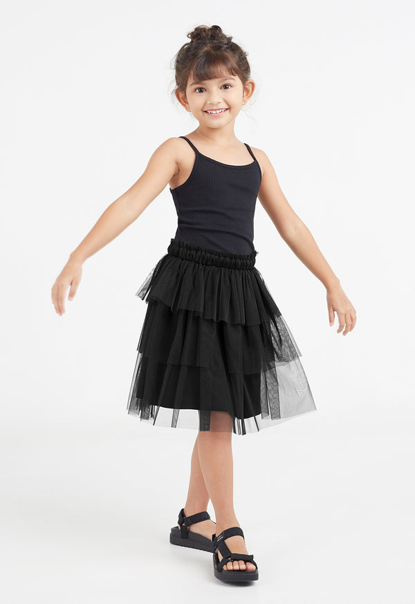 The young girl does a ballet pose wearing the Black Mesh Tiered Knee-Length Girls Skirt by Gen Woo