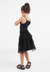 Back view of the young girl wearing the Black Mesh Tiered Knee-Length Girls Skirt by Gen Woo