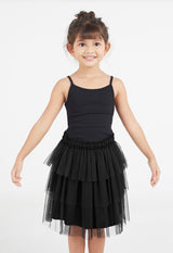 A close-up of the young girl posing wearing the Black Mesh Tiered Knee-Length Girls Skirt by Gen Woo