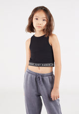 The young girl wears the Black Cropped Girls Tank Top by Gen Woo with sweatpants