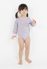 The young girl wears the Ditsy Floral Print Long Sleeve Babygrow by Gen Woo