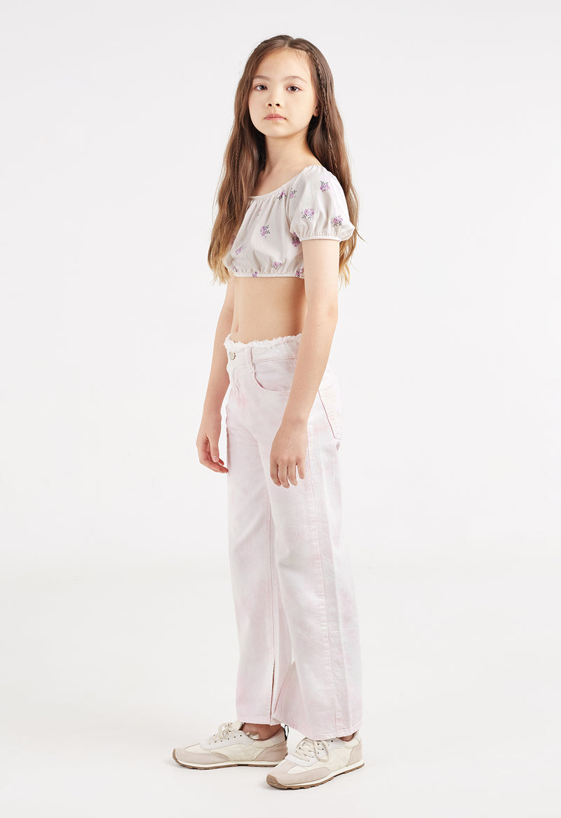 The young girl models the Girls Off-The-Shoulder Ditsy Crop Top by Gen Woo with jeans
