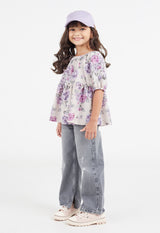 The young girl models the Pink and Purple Floral Bloom Girls Smock Top by Gen Woo