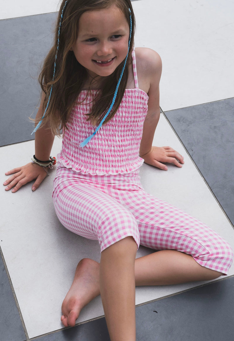 Young girl sits wearing the Gingham Shirred Strappy Girls Top by Gen Woo