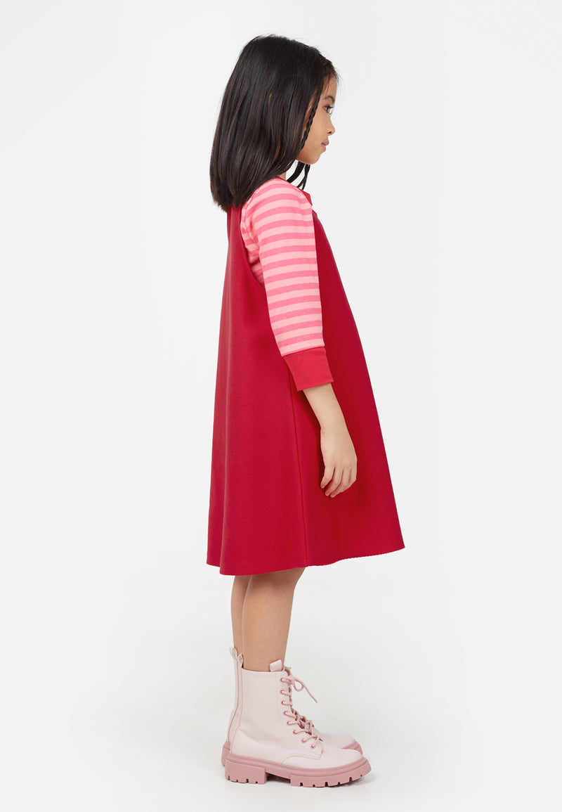 Young girl wears the Raspberry Red Twill Pinafore Dress by Gen Woo