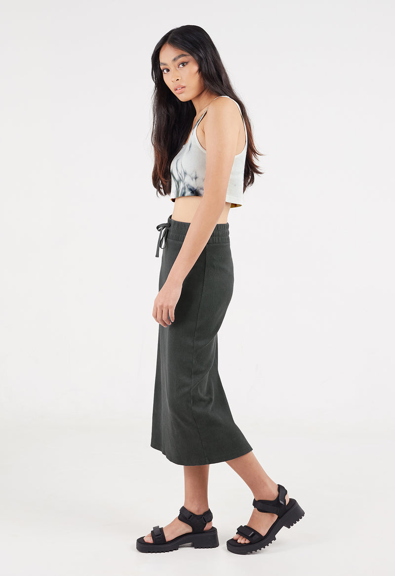 Ladies Skirt by Gen Woo. Our black midi rib skirt features elasticated waistband and functional drawstring. The calf length skirt too has a slit at the back along with washed out effect. Please note that each washed out garment will have colour shade variation. –Side view