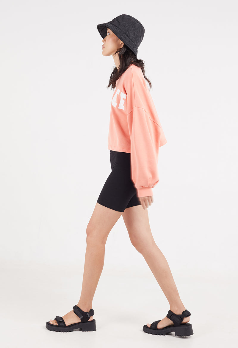 Side view of the model wearing the Salmon Cropped Slogan Sweater by Gen Woo 