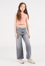 The young girl wears the Salmon Cropped Girls Tank Top by Gen Woo with high-waist jeans