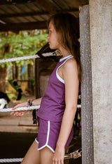 The young girl leans against a wall wearing the Girls Plum Retro Tank Top by Gen Woo