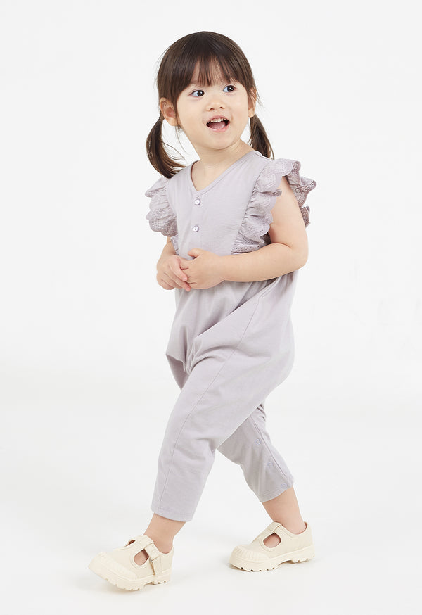 The young girl walks wearing the Lilac Broderie Trim Long Leg Romper by Gen Woo