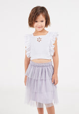 A close-up of the young girl posing wearing the Purple Mesh Tiered Knee-Length Girls Skirt by Gen Woo
