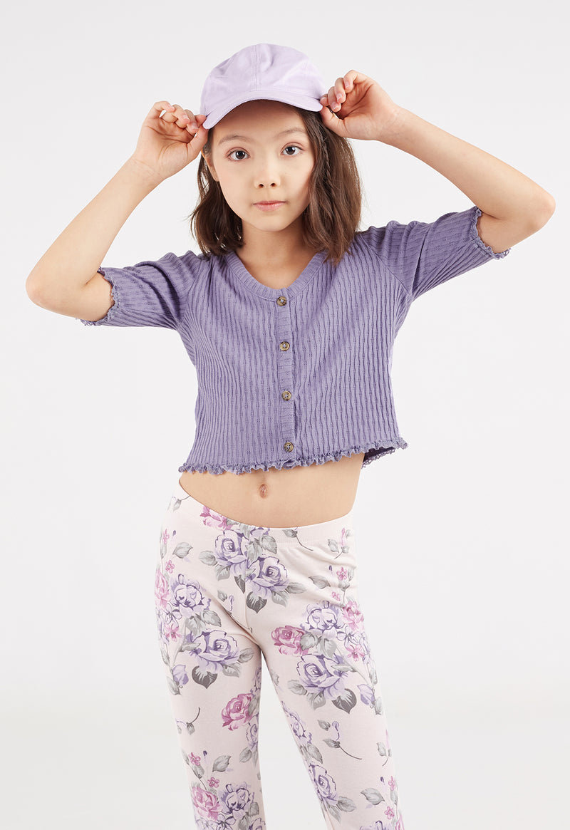 The young girl styles the Purple Pointelle Henley Girls Cropped Top by Gen Woo with floral print leggings