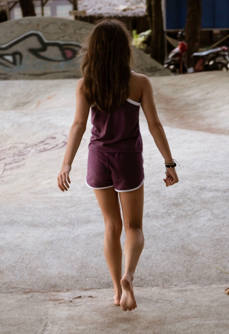Teenage girl walks away wearing the Purple and White Girls Retro Track Shorts by Gen Woo
