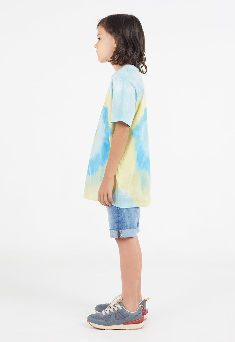 Side view as the young boy wears the Boys Blue and Yellow Spiral Tie-Dye T-Shirt by Gen Woo 