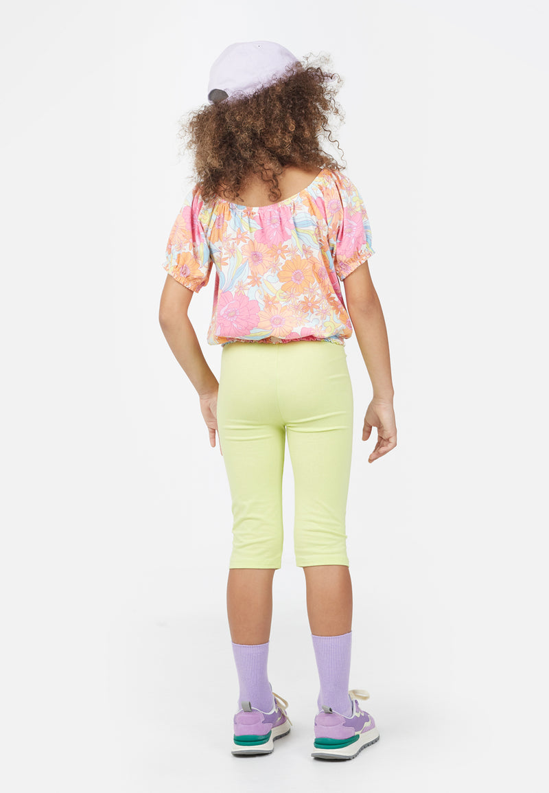 Back view as the young girl wears the Neon Lime Cropped Girls Leggings by Gen Woo 