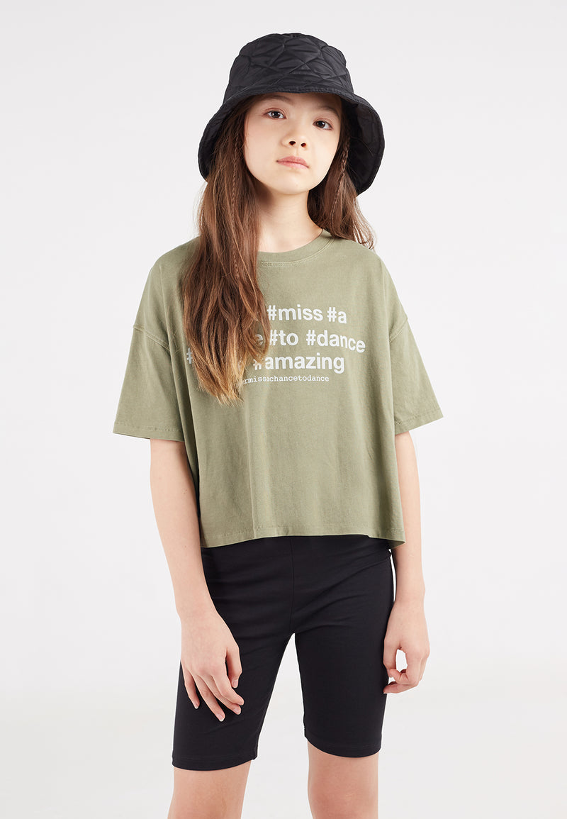 A close-up of the teen girl wearing the Khaki Hashtag Slogan Girls Boxy Cropped T-Shirt by Gen Woo