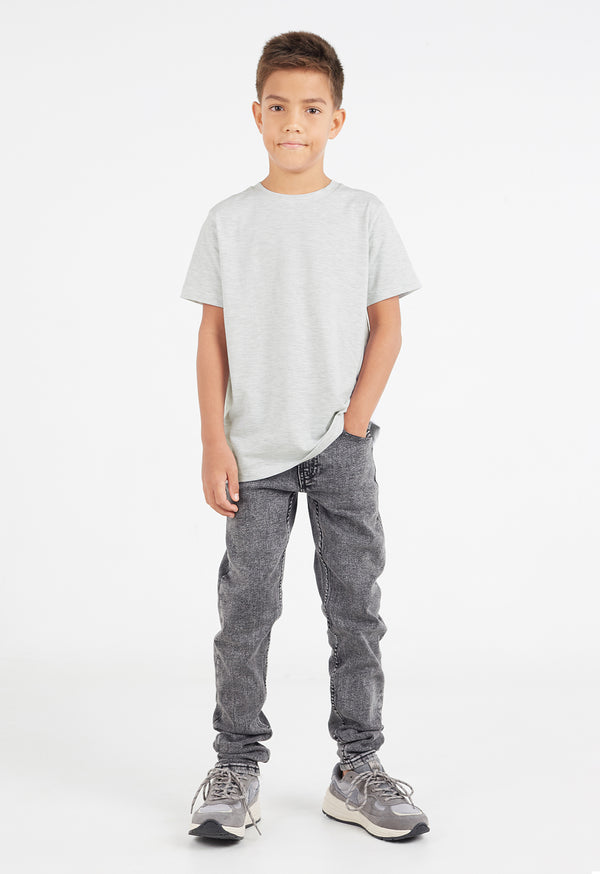The young boy wears the Boys Classic Crew Neck Grey Marl T-Shirt by Gen Woo with skinny jeans and trainers
