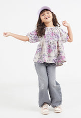 The young girl wears the Pink and Purple Floral Bloom Girls Smock Top by Gen Woo
