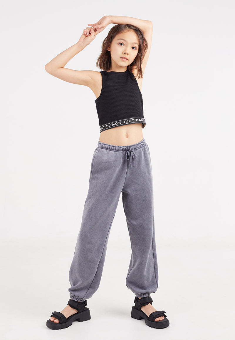 The young girl models the Black Cropped Girls Tank Top by Gen Woo