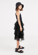 The young girl wears the Black Tulle Girls Midi Skirt by Gen Woo