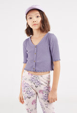 The young girl wears the Purple Pointelle Henley Girls Cropped Top by Gen Woo with floral print leggings