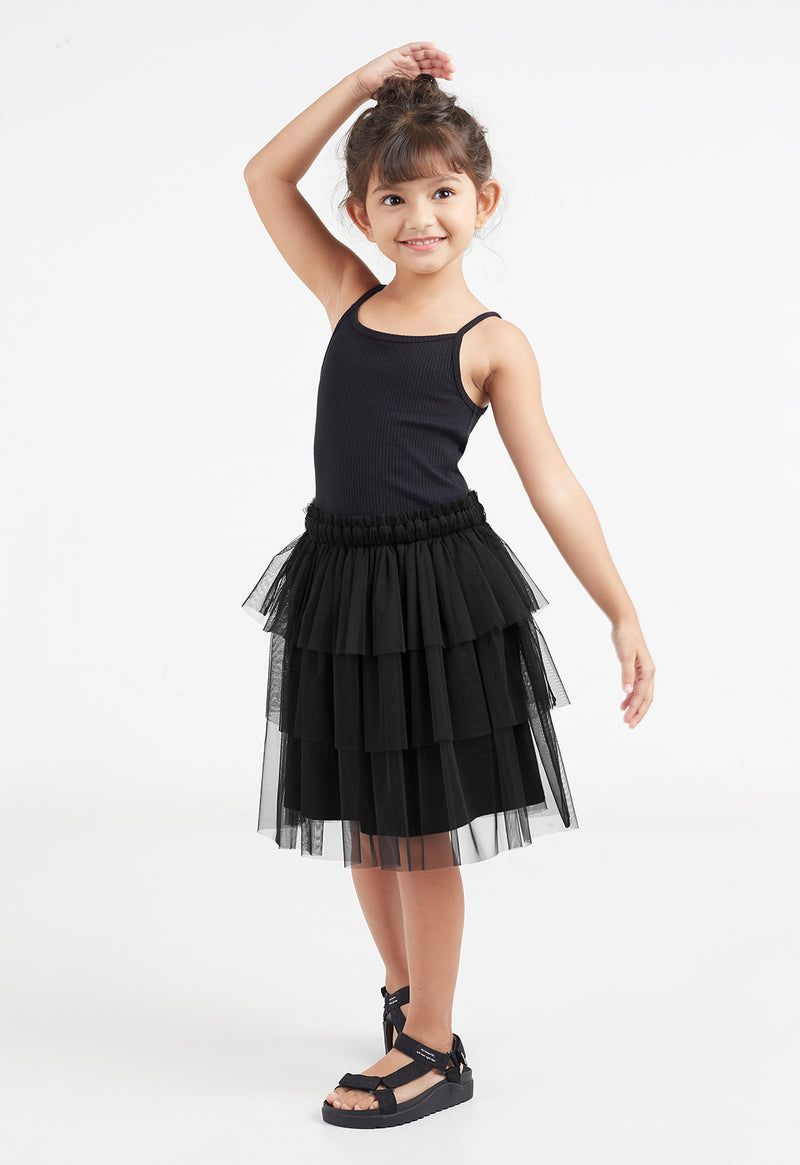 The young girl poses wearing the Black Mesh Tiered Knee-Length Girls Skirt by Gen Woo