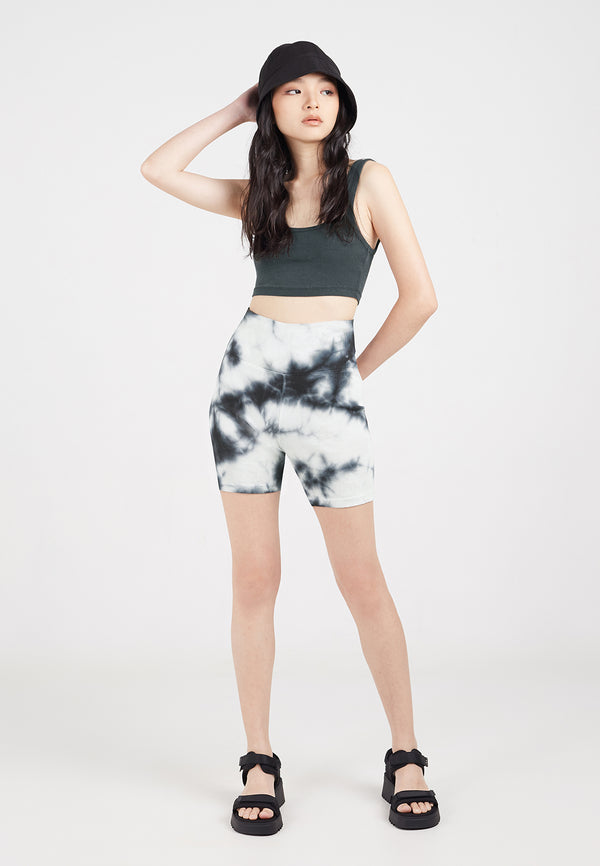 The model wears the Tie Dye Ribbed Cycling Shorts by Gen Woo with a bucket hat and chunky sandals 