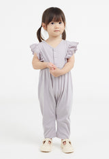The young girl wears the Lilac Broderie Trim Long Leg Romper by Gen Woo
