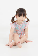 The young girl sits on the floor wearing the Ditsy Floral Print Flutter Sleeve Vest by Gen Woo