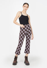 The teen girl wears the Plaid Flare Crop Trousers by Gen Woo with a black vest top and chunky boots