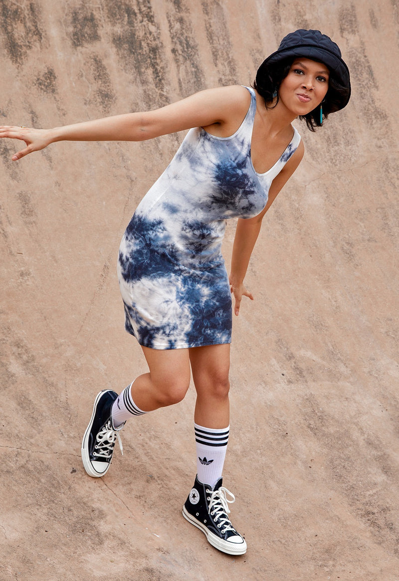 The model poses wearing the Ribbed Tie Dye Mini Dress by Gen Woo with a bucket hat and sneakers