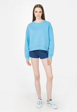 The model wears the Blue Relaxed Fit Crew Neck Ladies Sweater by Gen Woo with blue shorts and trainers