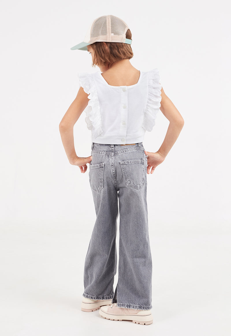 Back view of the young girl wearing the Broderie Trim Girls Flutter Crop Top by Gen Woo with denim jeans and a baseball cap