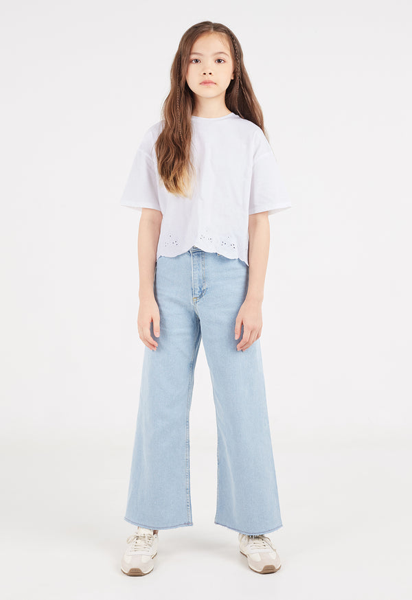 The teen girl wears the White Broderie Trim Girls T-Shirt by Gen Woo with flared jeans and sneakers