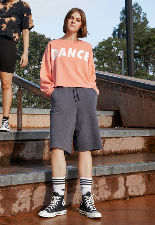 The model wears the Ladies Elasticated Bermuda Lounge Shorts by Gen Woo with a sweater and sneakers