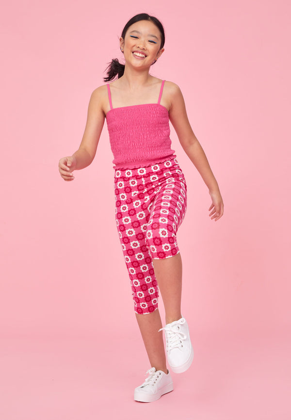 Teenage girl skips wearing the Pink Checkerboard Retro Floral Print Girls Leggings by Gen Woo