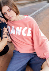 The model poses wearing the Salmon Cropped Slogan Sweater by Gen Woo 