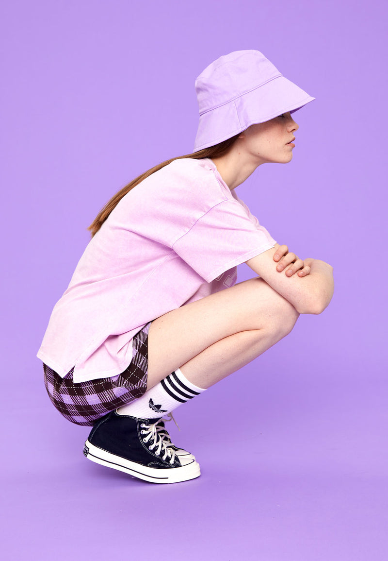 Teenage girl bends down wearing the Purple Plaid Girls Mini Skort by Gen Woo